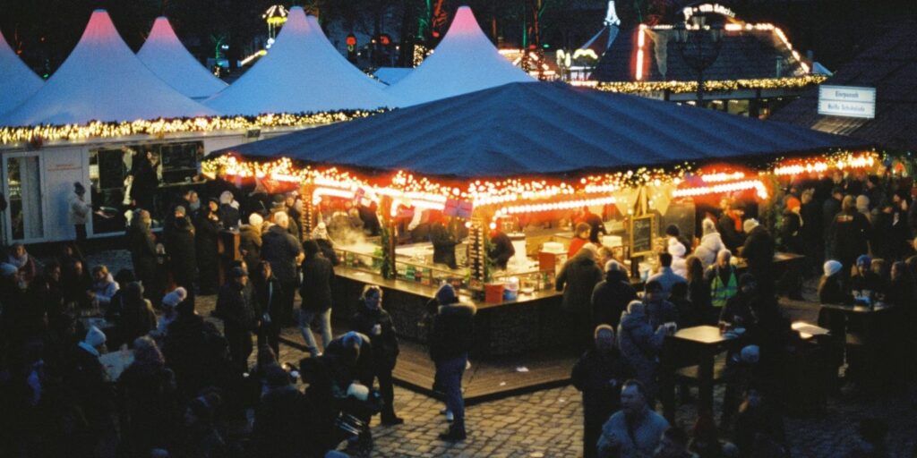 Rij verlichte kerstmarktkraampjes met bezoekers in de avond